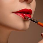 Beautiful female lips with make-up and brush on white. Makeup artist working process